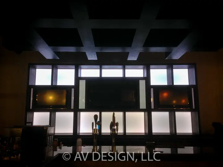 Backlit custom bar-back shelving wall with built-in TVs and lit panels in a San Antonio restaurant