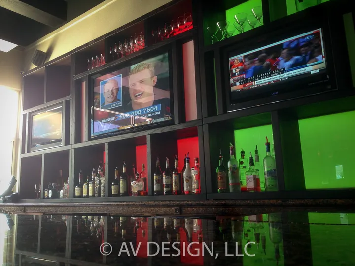 Custom bar-back wall with built-in TVs and red and green accent lighting