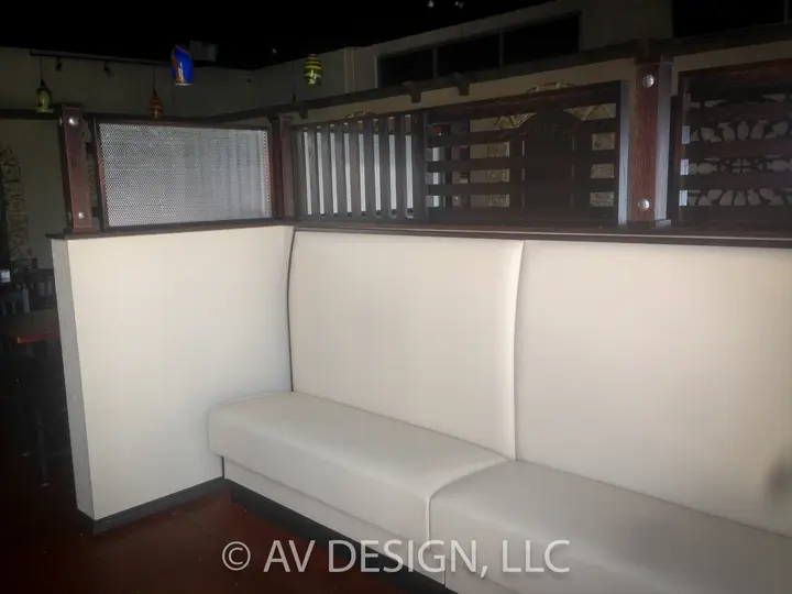 Built-in upholstered banquette booth topped with a wood-framed metal mesh screen