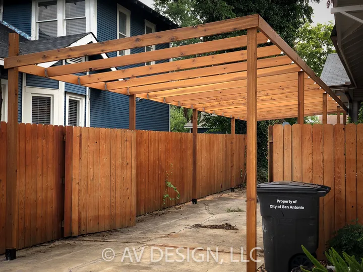 Cedar carport with slatted roof framing beside a privacy fence