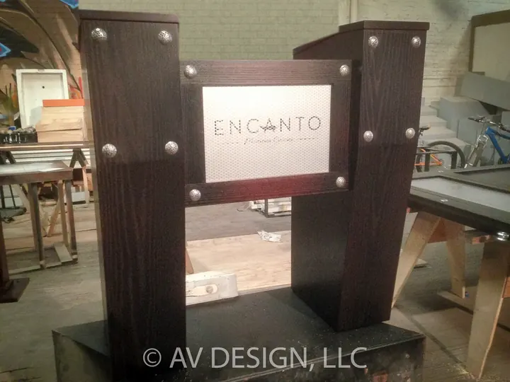 Custom stained oak restaurant host stand with metal rivets and an inset logo panel