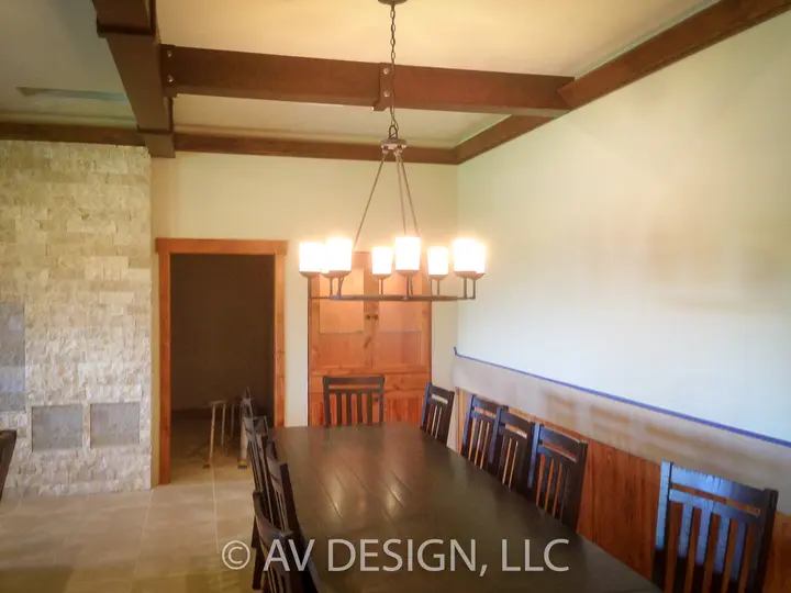 Dining room with stained wood wainscoting, exposed ceiling beams and a stone accent wall