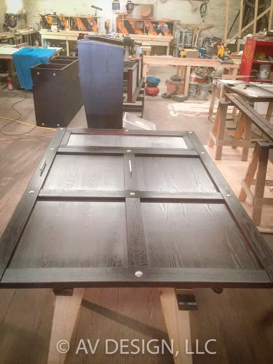 Hand-built paneled door in stained oak laid out on sawhorses in the shop
