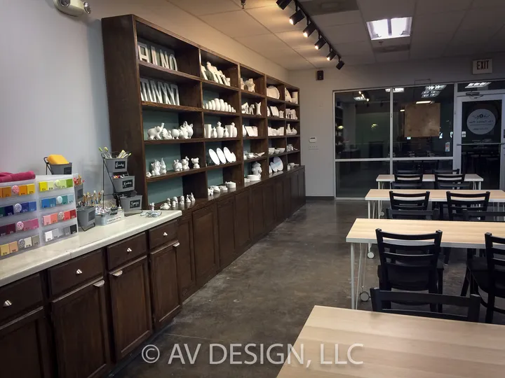 Long stained wood shelving and counter run inside a pottery studio