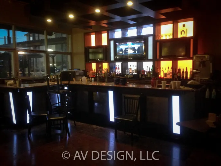 Restaurant bar with a backlit custom back wall and illuminated end panels