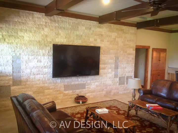 Living room with a stone accent wall, mounted TV and stained wood trim