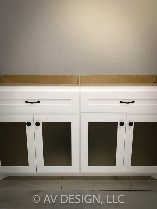 White built-in base cabinets with glass panel doors and black knobs