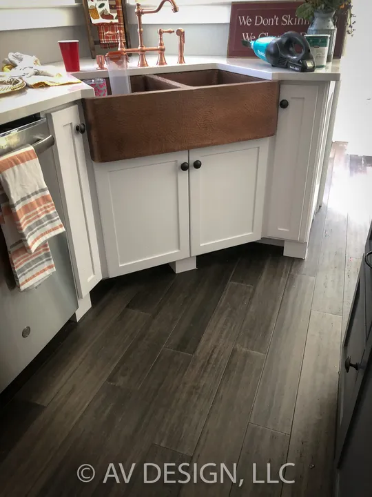 White kitchen cabinets built around a copper farmhouse sink